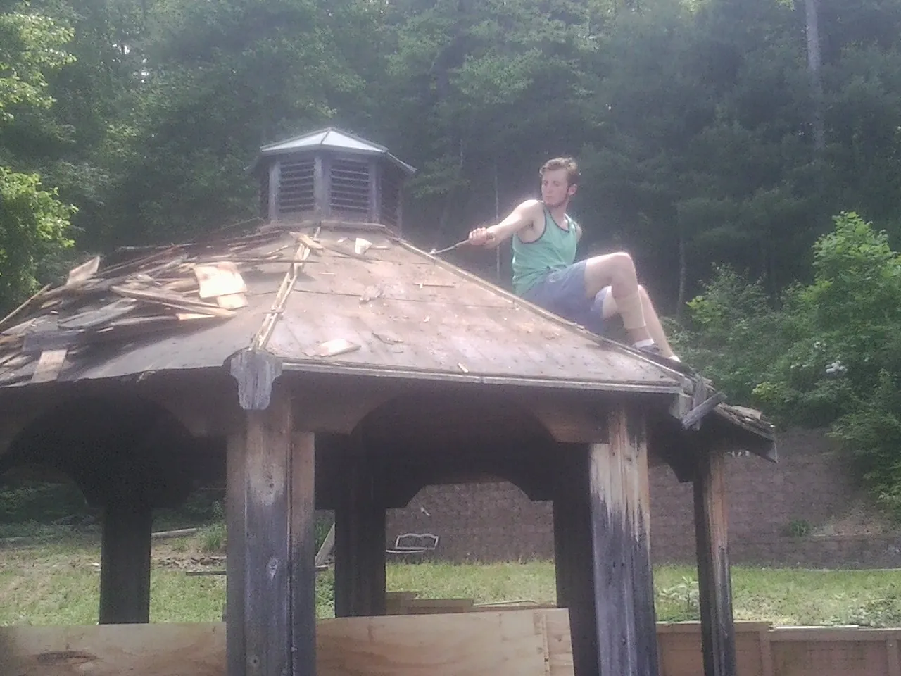 Tearing the old roof off a wooden gazebo before new shakes in Central Falls