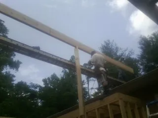 Carpenter setting a ridge beam over a new addition frame — Ice Dam Removal by Roofing Brothers in Central Falls