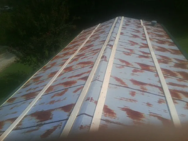 Rusted metal roof panels with new wood purlins before replacement — Storm Damage Roof Repair in Central Falls by Roofing Brothers