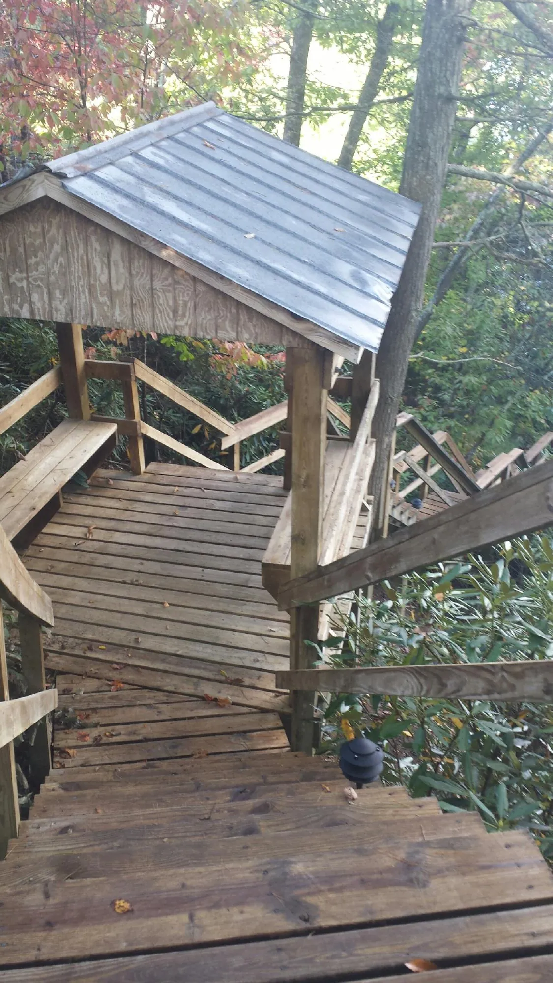 Metal roofed shelter over wooden steps on a wooded walkway — Skylight Repair & Installation work by our crew in Central Falls