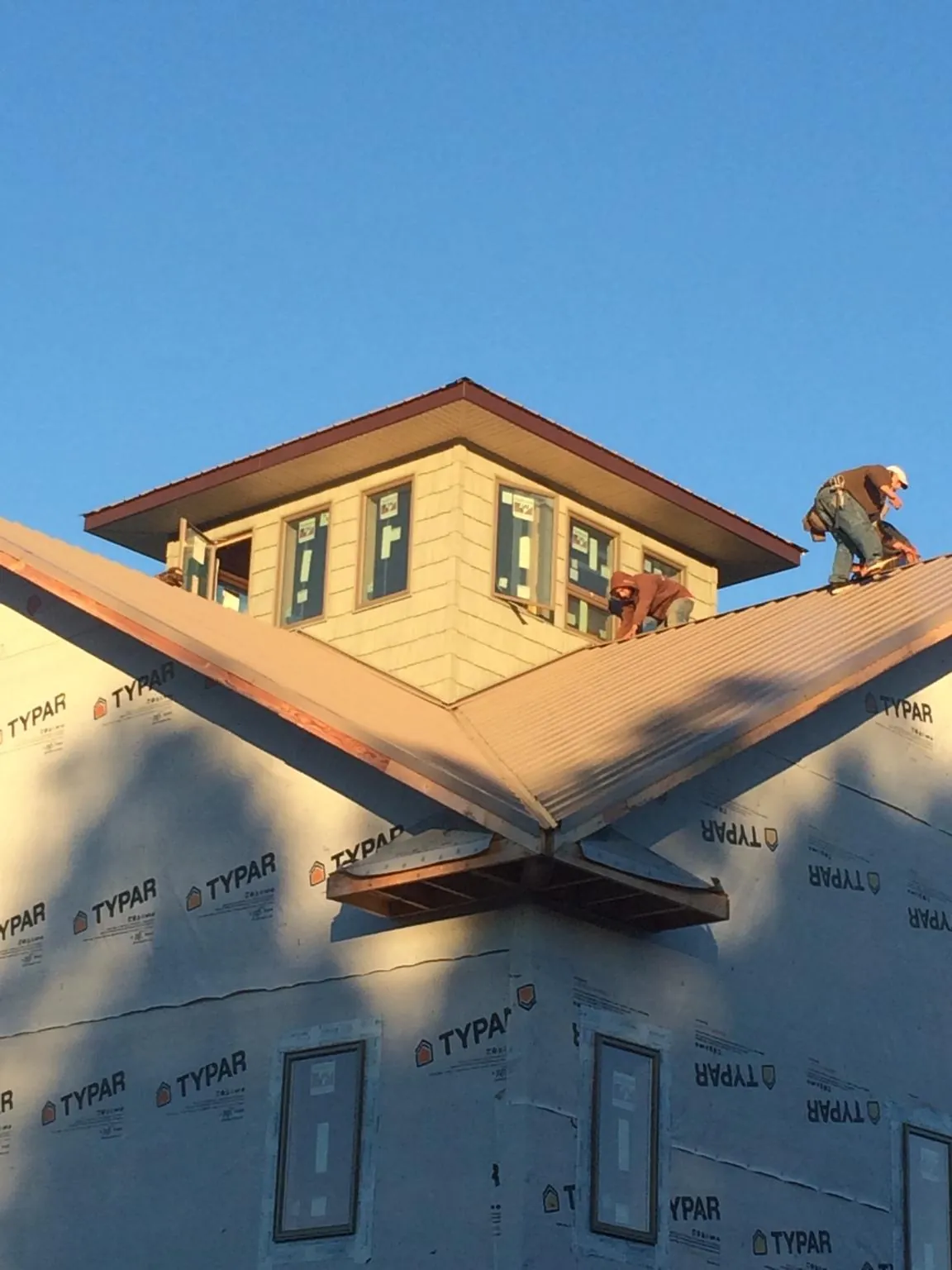 Roofers working around a rooftop cupola on a new metal roof at sunset — Roof Waterproofing in Central Falls by Roofing Brothers